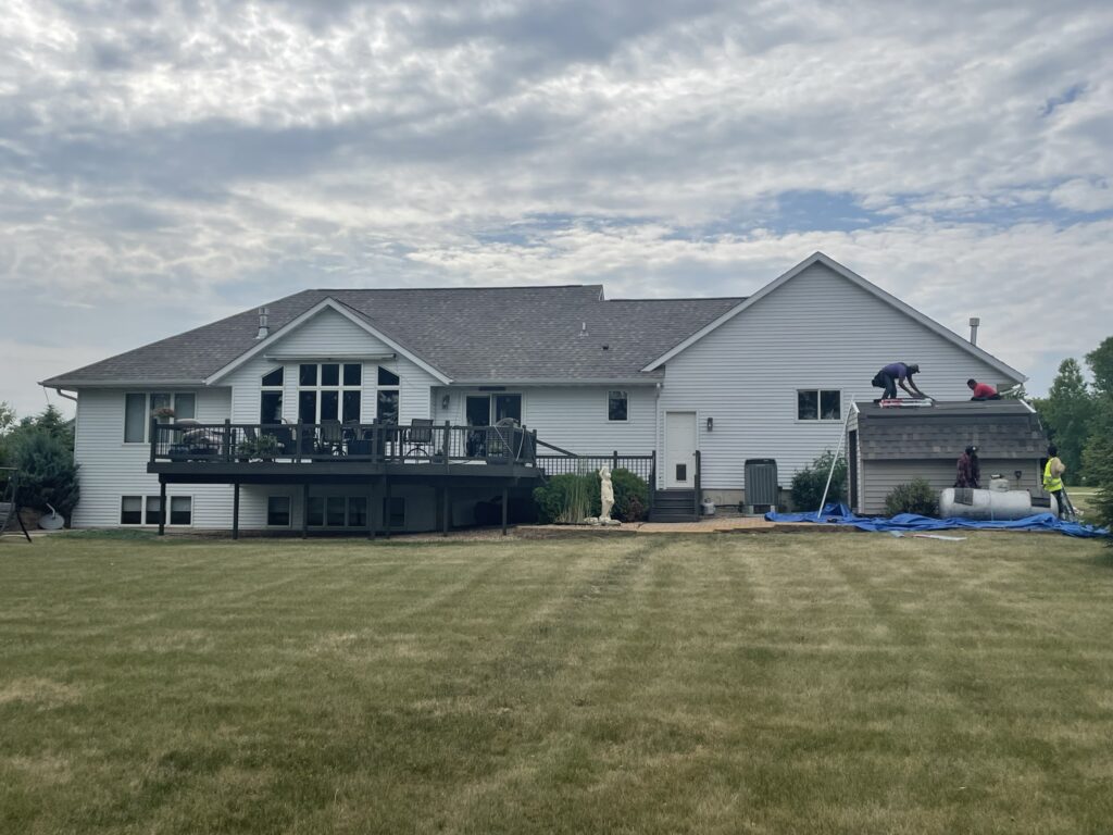 The home's roof is already replaced and the site kept clean — lawn tarped, beds covered — with just the detached shed left to re-roof before the whole job's buttoned up.